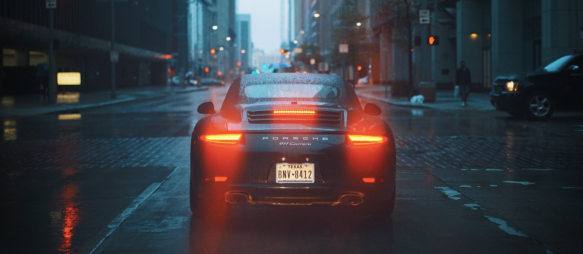 A Porsche vehicle shot from behind on a rainy night